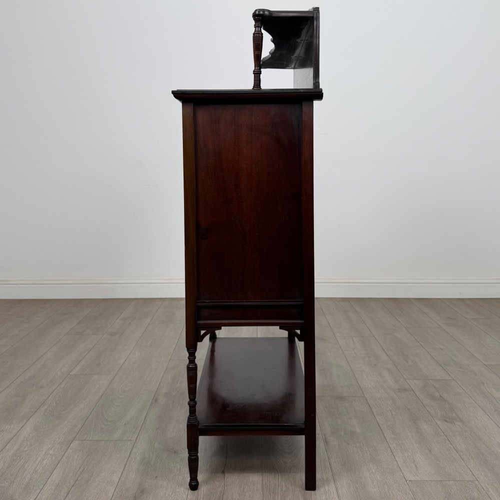An Edwardian mahogany display cabinet featuring twin diamond-glazed doors, an upper shelf gallery, decorative fretwork, turned support legs, and an undertier. View IV