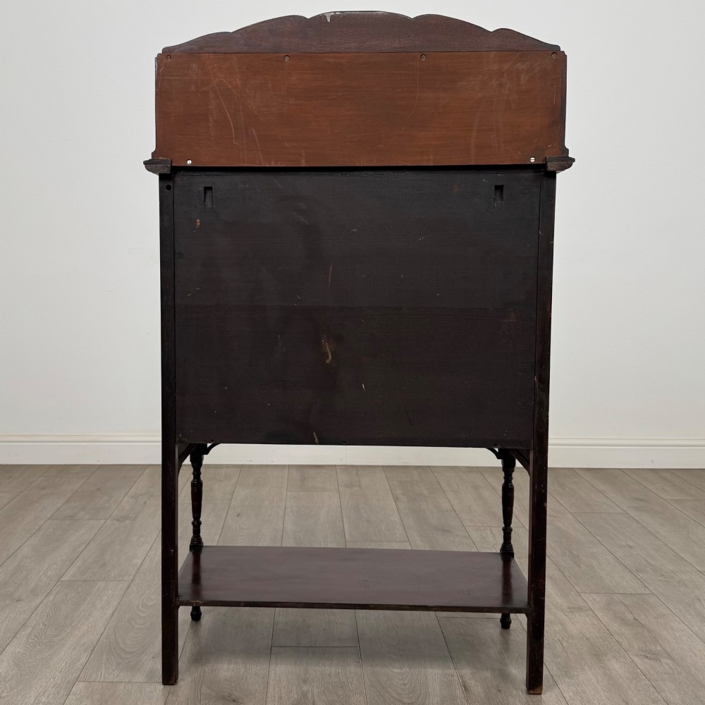 An Edwardian mahogany display cabinet featuring twin diamond-glazed doors, an upper shelf gallery, decorative fretwork, turned support legs, and an undertier. View VI