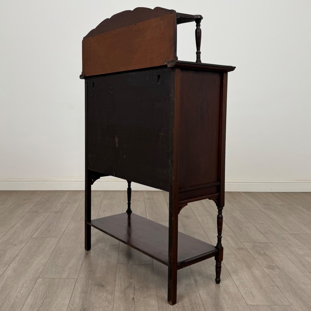 An Edwardian mahogany display cabinet featuring twin diamond-glazed doors, an upper shelf gallery, decorative fretwork, turned support legs, and an undertier. View VII