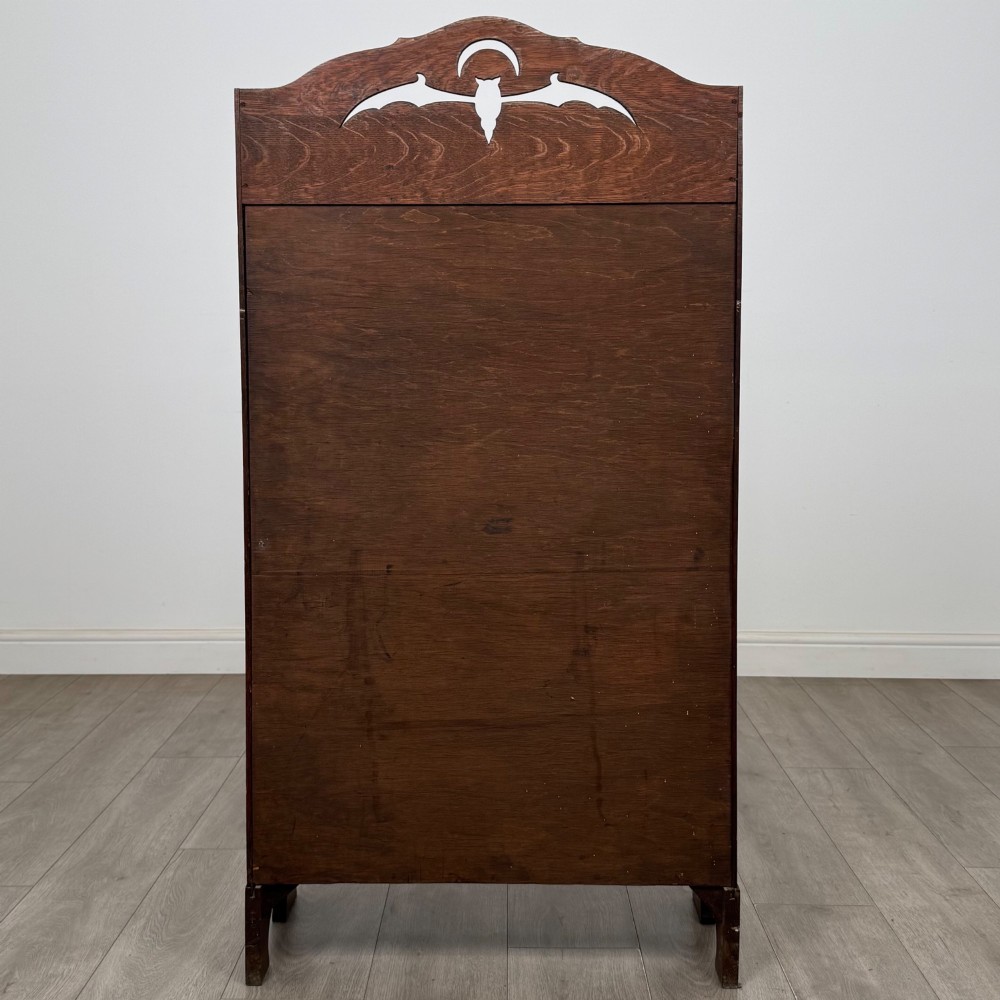 An antique Arts and Crafts oak writing bureau featuring a slant drop-front desk, a pierced cresting top rail, dark iron strap hardware, an open shelf, and lower double doors. View VII