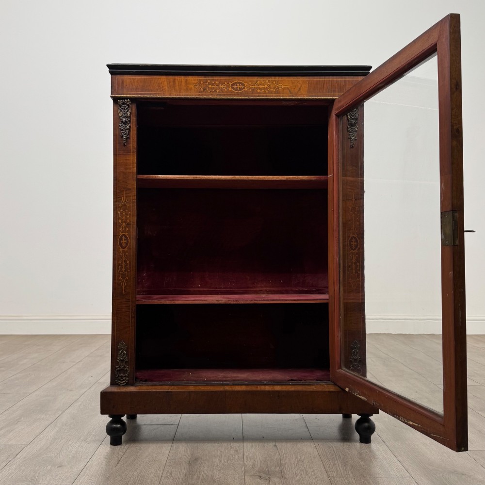 A 19th-century Victorian walnut pier cabinet featuring floral marquetry inlays, gilded metal mounts, and a single glazed door revealing interior shelves. View II