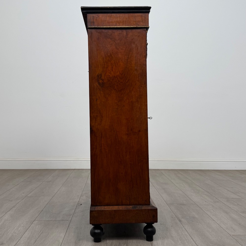 A 19th-century Victorian walnut pier cabinet featuring floral marquetry inlays, gilded metal mounts, and a single glazed door revealing interior shelves. View VIII
