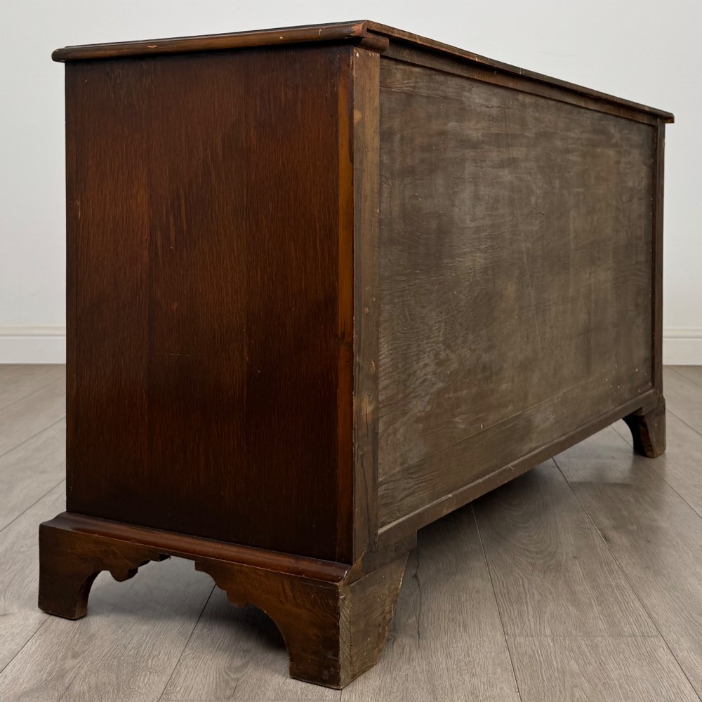 A dark oak sideboard featuring two carved upper drawers above panelled cupboard doors with decorative iron hinges and wooden knobs. View V