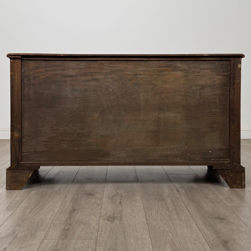 A dark oak sideboard featuring two carved upper drawers above panelled cupboard doors with decorative iron hinges and wooden knobs. View VI