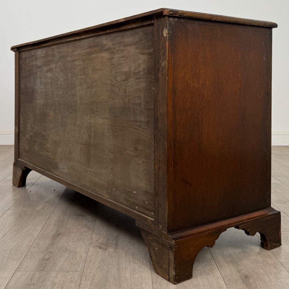 A dark oak sideboard featuring two carved upper drawers above panelled cupboard doors with decorative iron hinges and wooden knobs. View VII