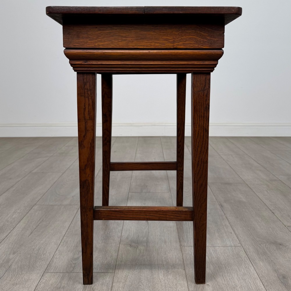 An Edwardian oak side table featuring a rectangular top, moulded frieze, tapered square legs, and low side stretchers. View III