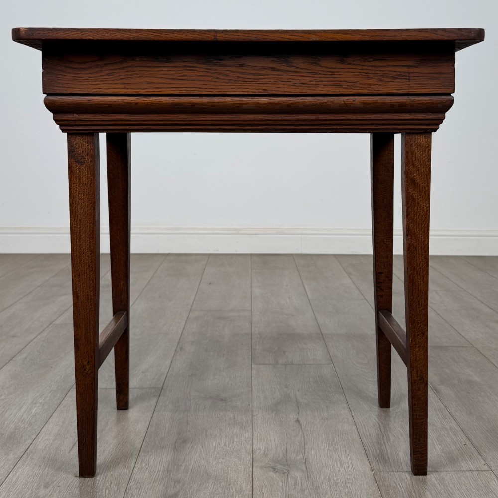 An Edwardian oak side table featuring a rectangular top, moulded frieze, tapered square legs, and low side stretchers. View V