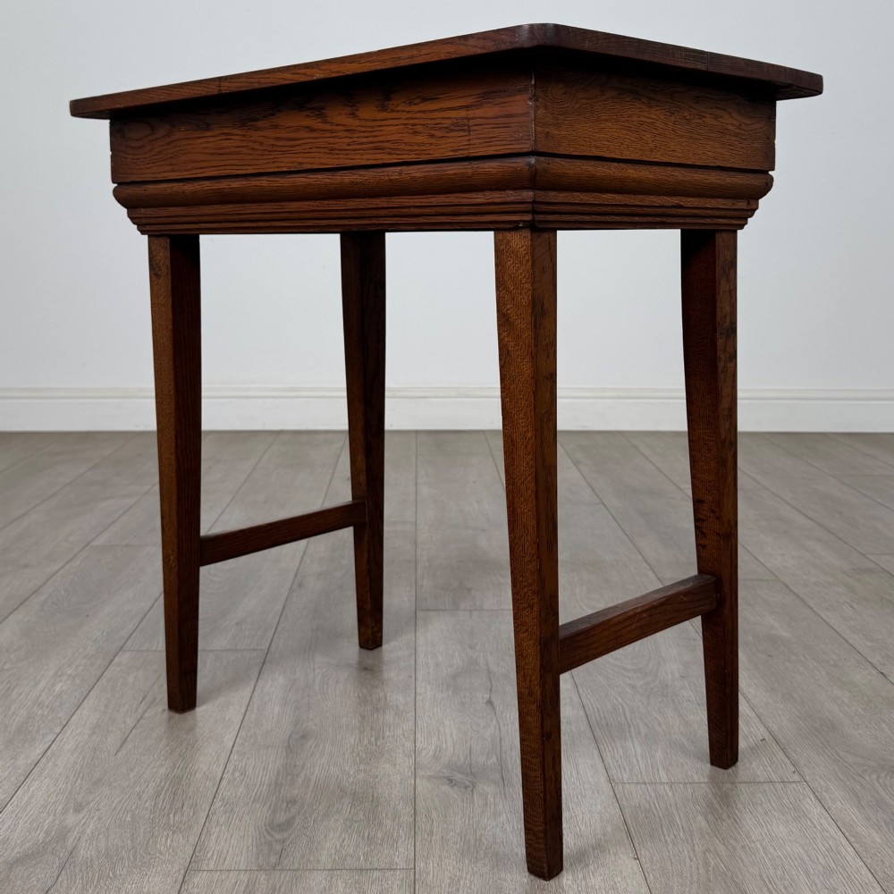 An Edwardian oak side table featuring a rectangular top, moulded frieze, tapered square legs, and low side stretchers. View VI