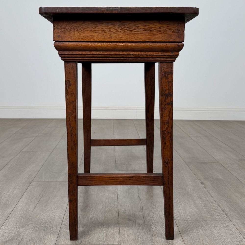 An Edwardian oak side table featuring a rectangular top, moulded frieze, tapered square legs, and low side stretchers. View VII