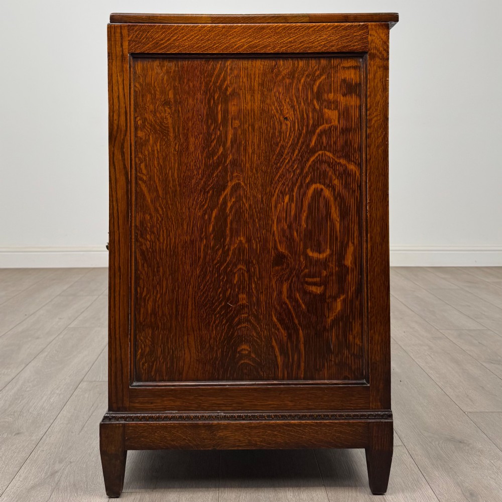 An antique Edwardian oak chest featuring four full-width drawers with brass teardrop handles and tapered legs. View III