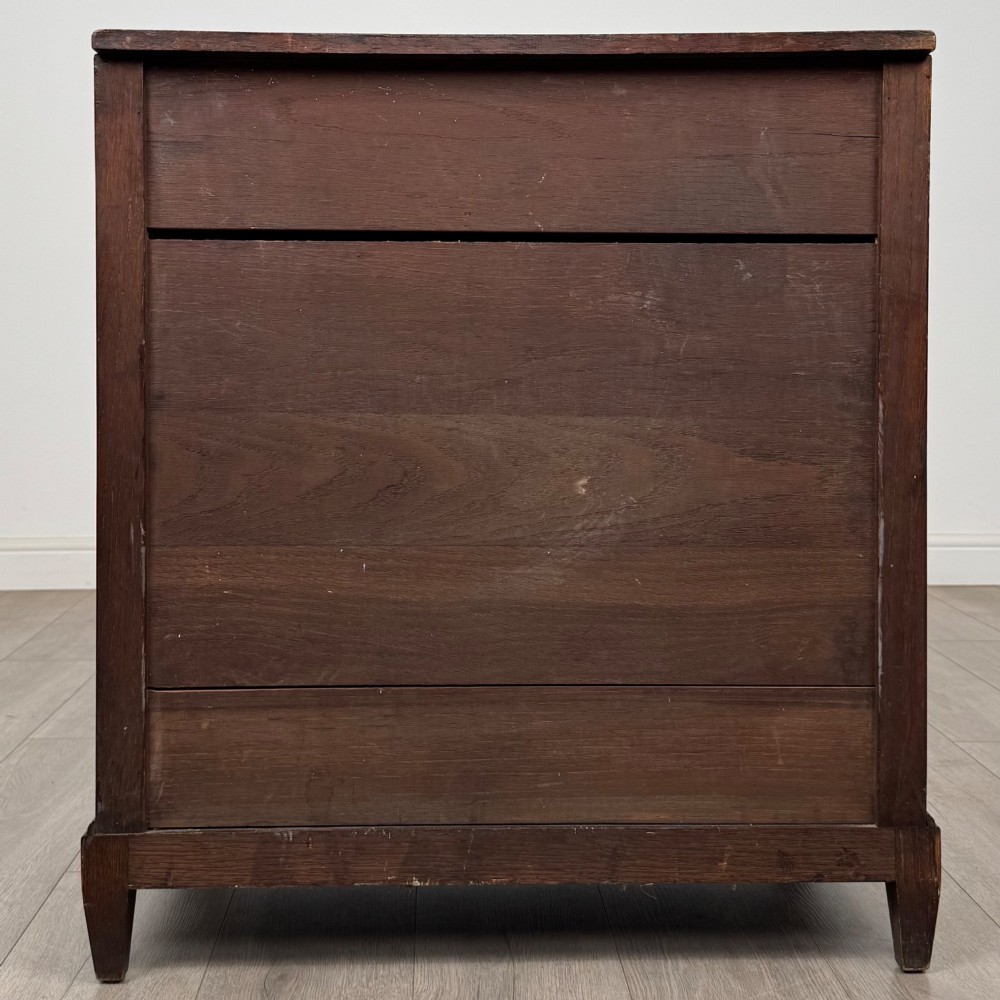 An antique Edwardian oak chest featuring four full-width drawers with brass teardrop handles and tapered legs. View V