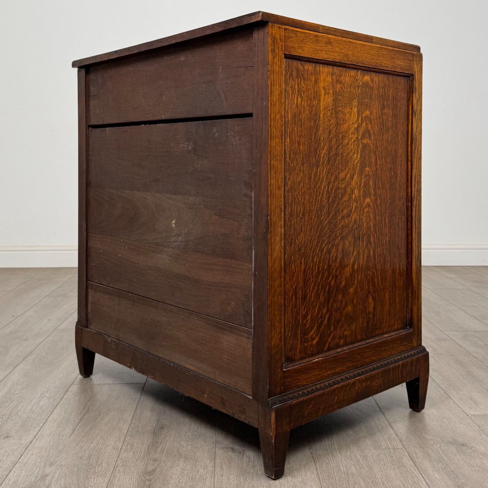 An antique Edwardian oak chest featuring four full-width drawers with brass teardrop handles and tapered legs. View VI