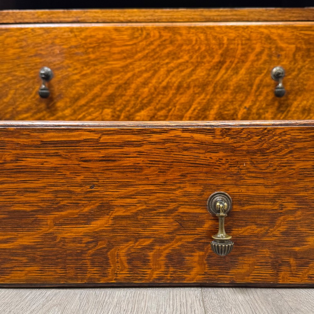 An antique Edwardian oak chest featuring four full-width drawers with brass teardrop handles and tapered legs. View XI