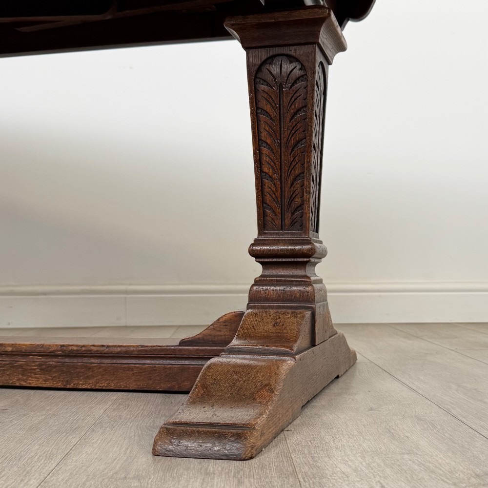 A dark oak draw leaf dining table featuring two extendable leaves, carved pedestal supports, and a low connecting stretcher base. View VII