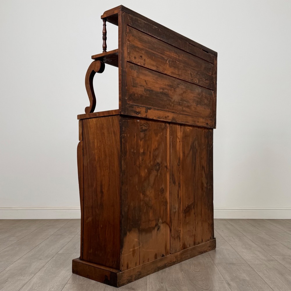 An antique Regency mahogany chiffonier featuring an upper two-tier shelf structure, a long drawer with star-shaped brass pulls, and a lower panelled double cupboard on a plinth base. View V