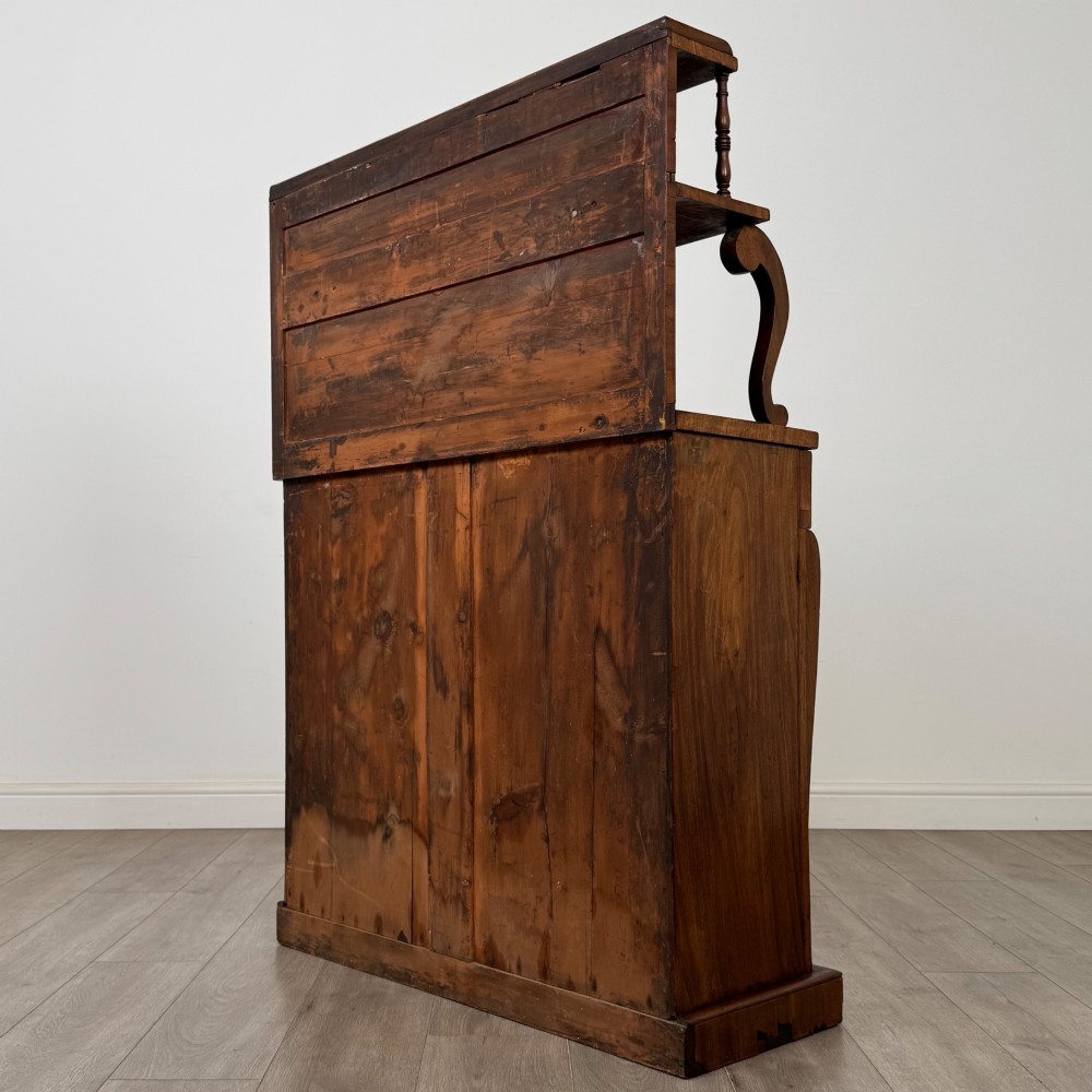 An antique Regency mahogany chiffonier featuring an upper two-tier shelf structure, a long drawer with star-shaped brass pulls, and a lower panelled double cupboard on a plinth base. View VII