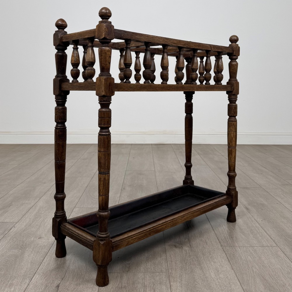An Edwardian dark oak umbrella stand featuring turned corner posts, a top rail filled with turned spindles, and a lower drip tray. View IV