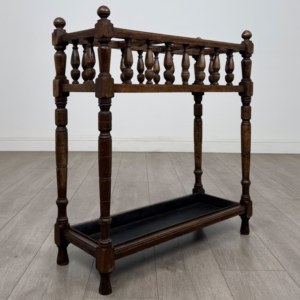 An Edwardian dark oak umbrella stand featuring turned corner posts, a top rail filled with turned spindles, and a lower drip tray. View VIII