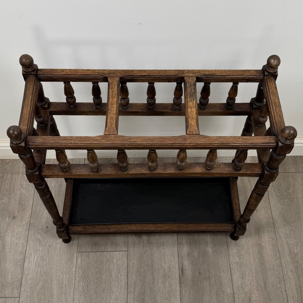 An Edwardian dark oak umbrella stand featuring turned corner posts, a top rail filled with turned spindles, and a lower drip tray. View IX