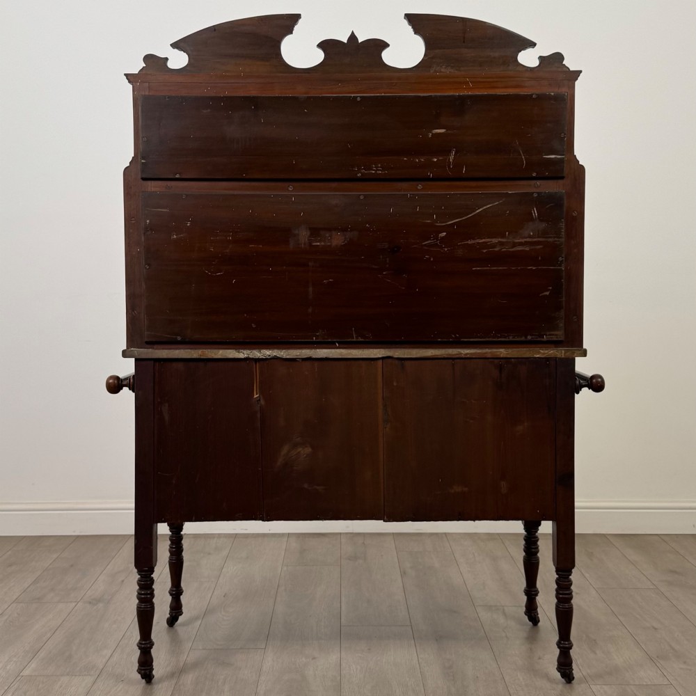 An Edwardian walnut washstand featuring a red marble splashback, mirror gallery top, double cupboard doors with burr walnut panels, and turned legs on castors. View VI