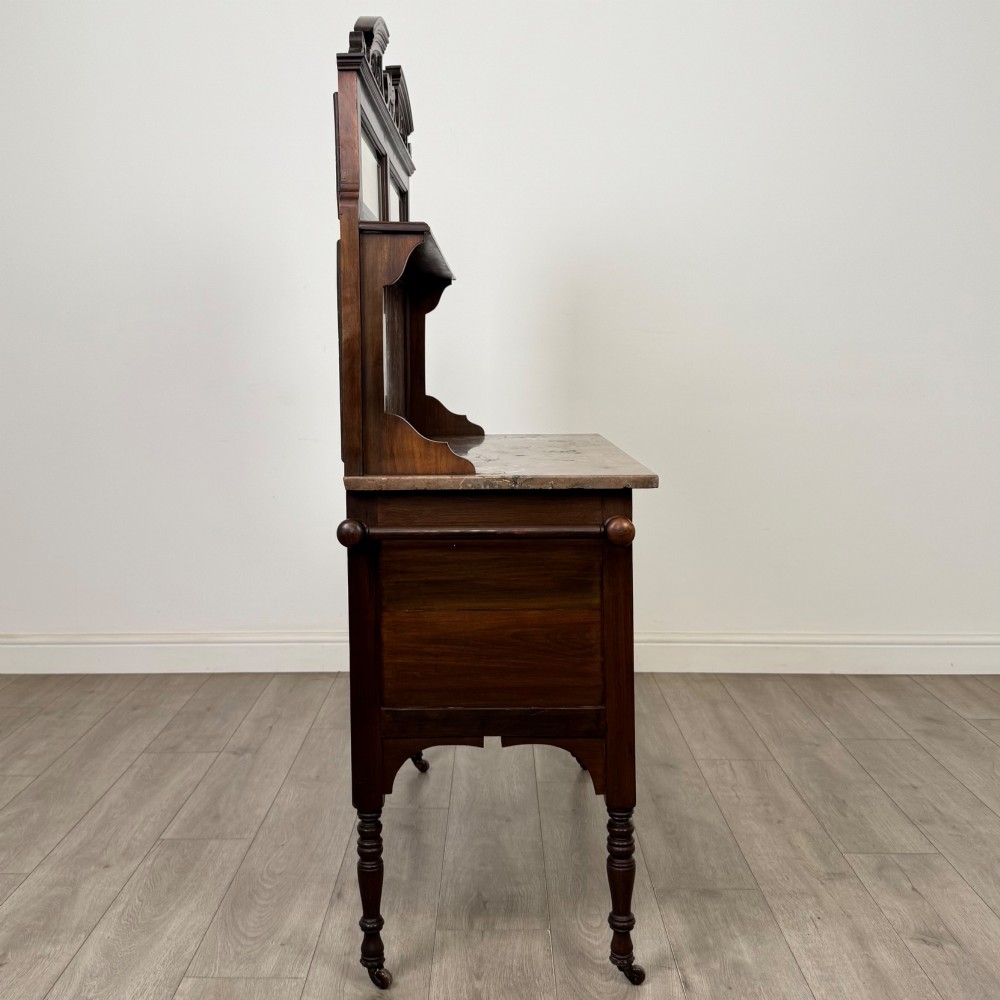 An Edwardian walnut washstand featuring a red marble splashback, mirror gallery top, double cupboard doors with burr walnut panels, and turned legs on castors. View VIII