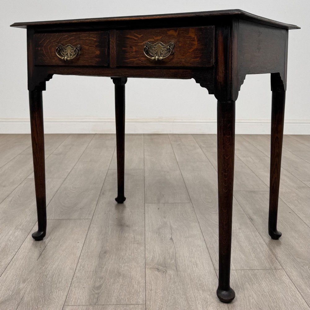 A dark oak Edwardian side table featuring two drawers with brass handles and tapered legs ending in pad feet. View II