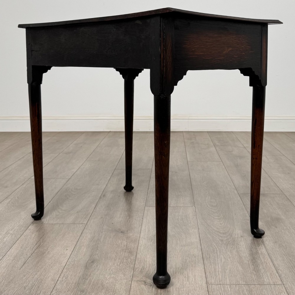 A dark oak Edwardian side table featuring two drawers with brass handles and tapered legs ending in pad feet. View VI