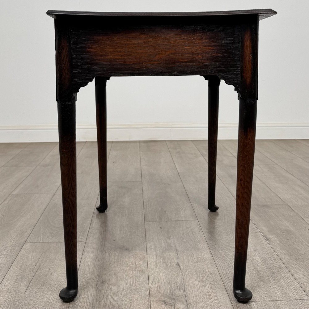 A dark oak Edwardian side table featuring two drawers with brass handles and tapered legs ending in pad feet. View VII