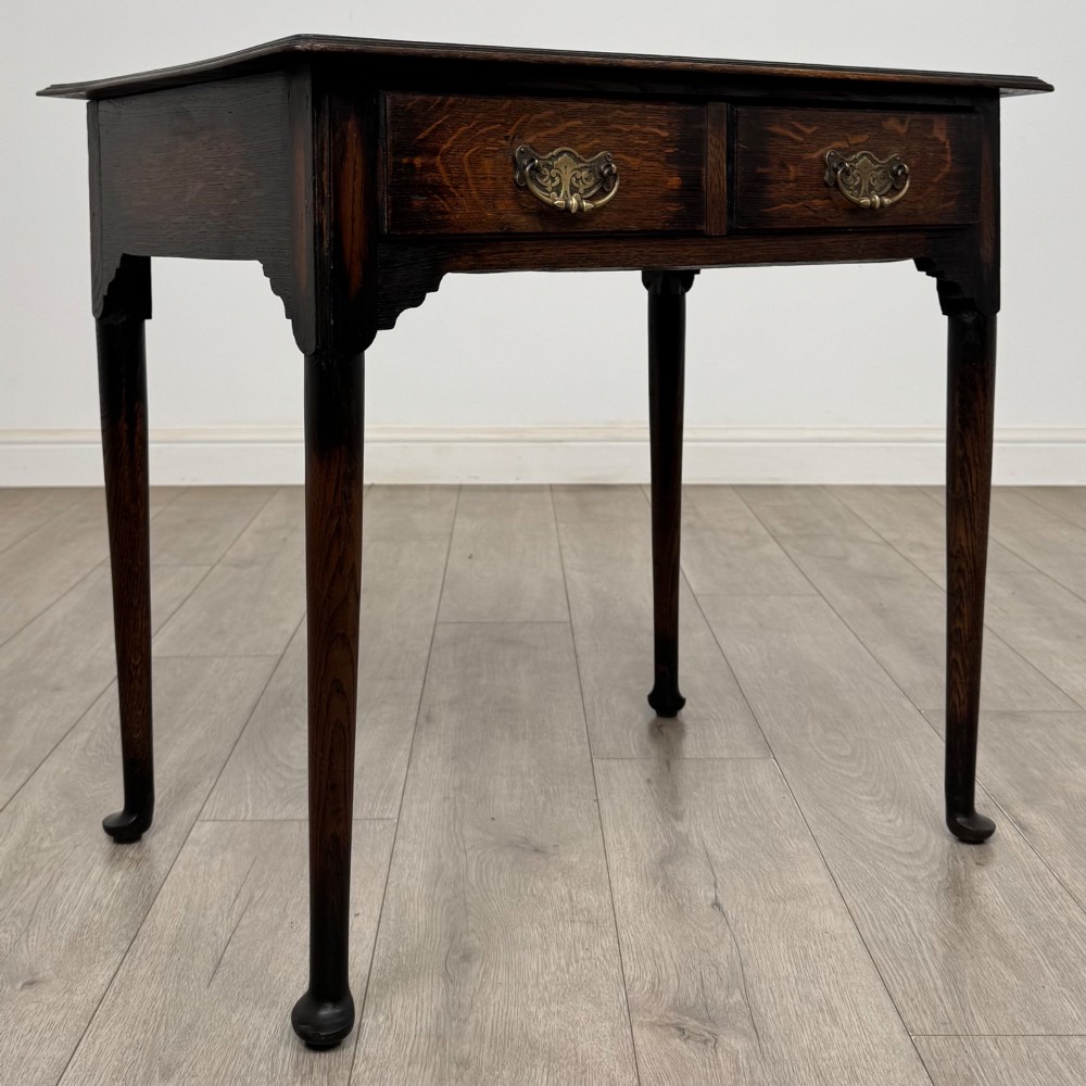A dark oak Edwardian side table featuring two drawers with brass handles and tapered legs ending in pad feet. View VIII