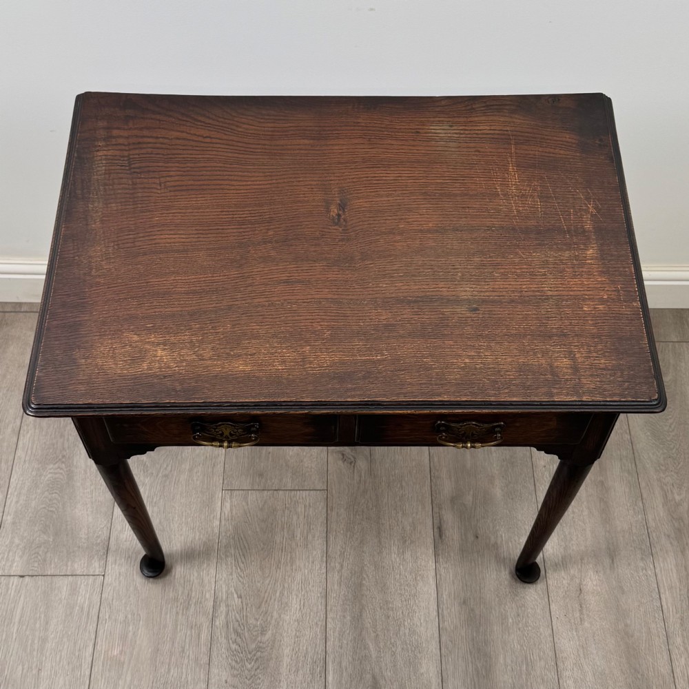 A dark oak Edwardian side table featuring two drawers with brass handles and tapered legs ending in pad feet. View IX
