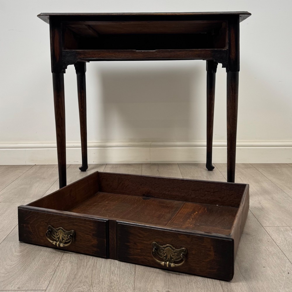 A dark oak Edwardian side table featuring two drawers with brass handles and tapered legs ending in pad feet. View X