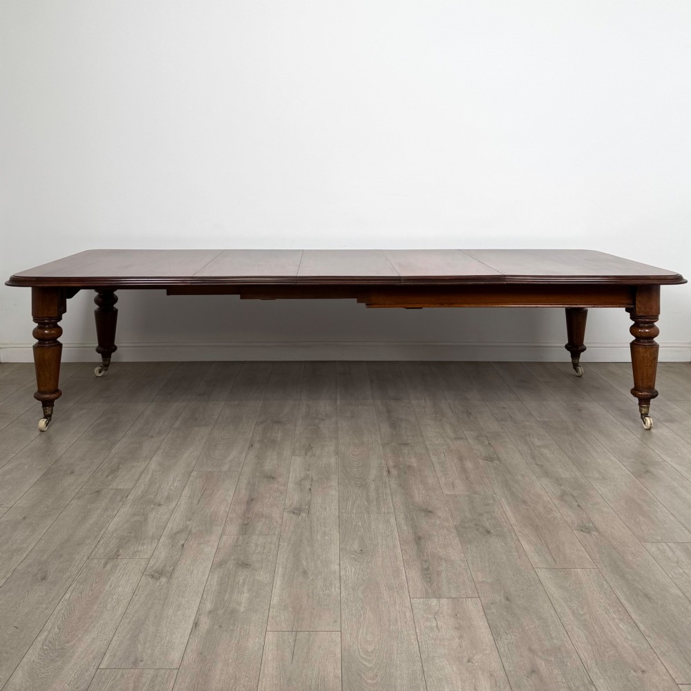 A large 19th-century Victorian mahogany extending dining table with rounded corners, turned legs, and brass castors.