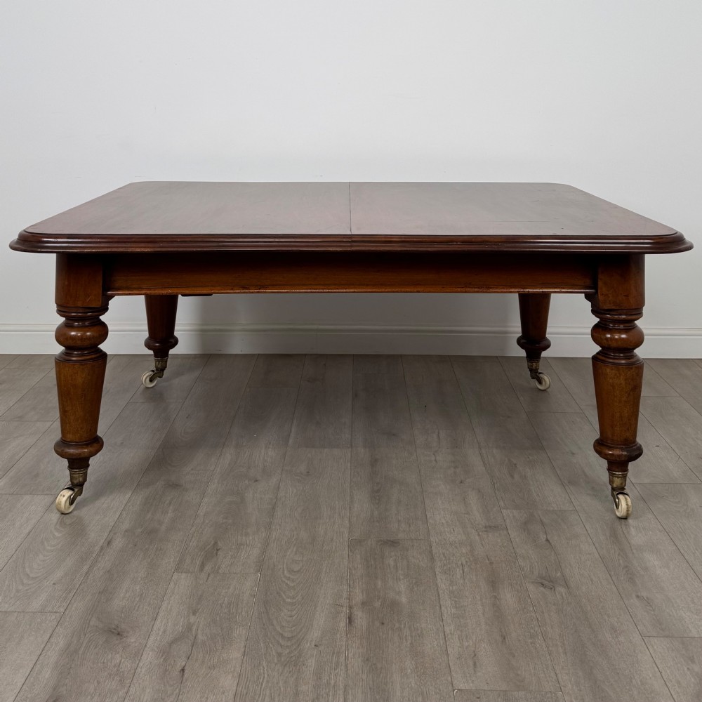 A large 19th-century Victorian mahogany extending dining table with rounded corners, turned legs, and brass castors. View IV