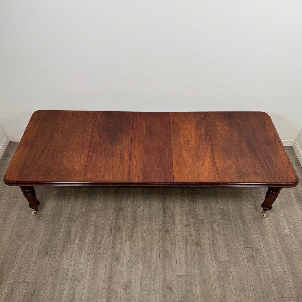 A large 19th-century Victorian mahogany extending dining table with rounded corners, turned legs, and brass castors. View VI