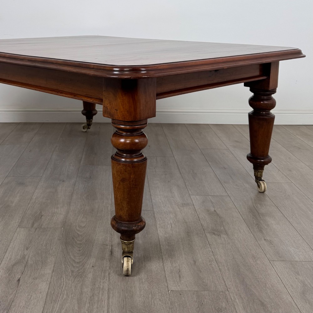 A large 19th-century Victorian mahogany extending dining table with rounded corners, turned legs, and brass castors. View VII