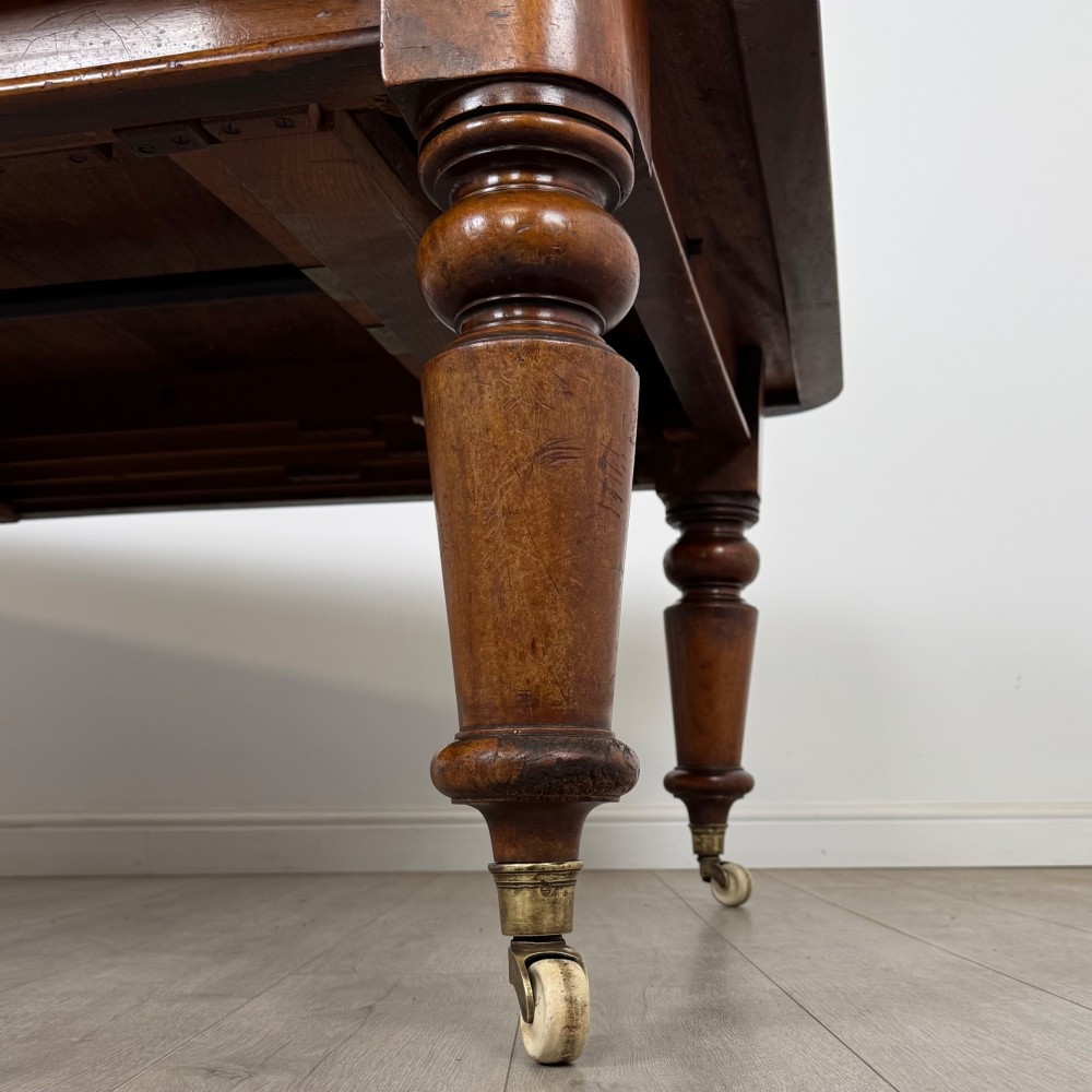 A large 19th-century Victorian mahogany extending dining table with rounded corners, turned legs, and brass castors. View VIII