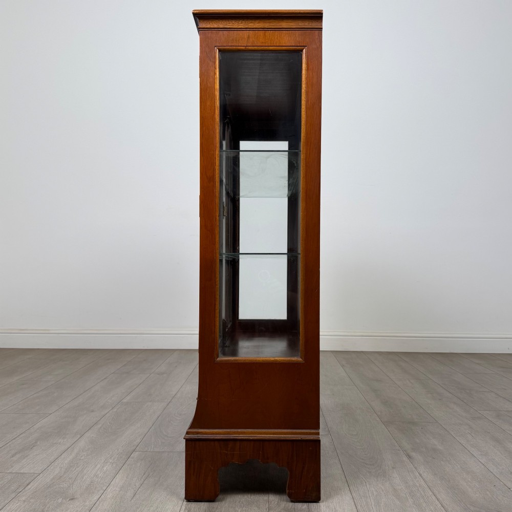 A 20th-century burr walnut display cabinet featuring two glazed doors with arched detail above two drawers on bracket feet. View IV