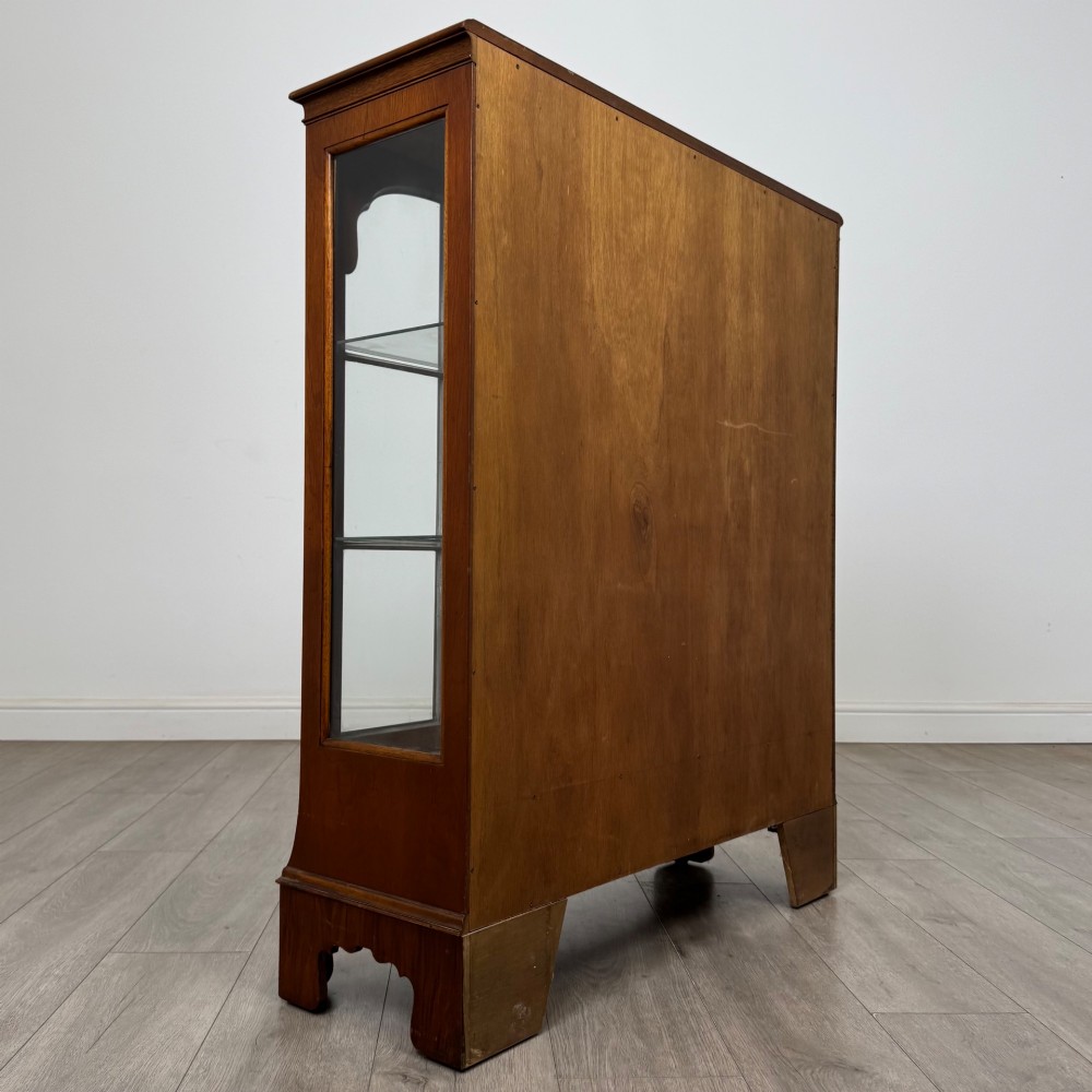 A 20th-century burr walnut display cabinet featuring two glazed doors with arched detail above two drawers on bracket feet. View V