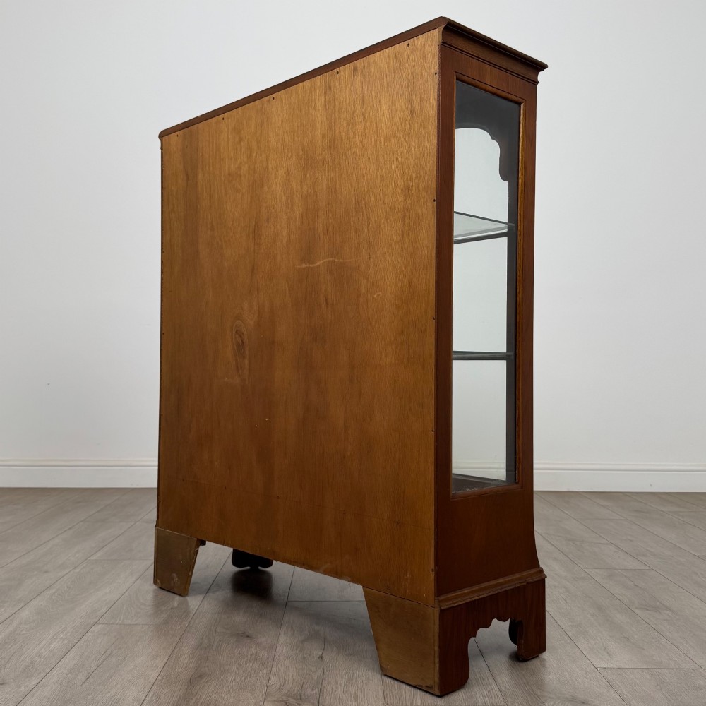 A 20th-century burr walnut display cabinet featuring two glazed doors with arched detail above two drawers on bracket feet. View VII