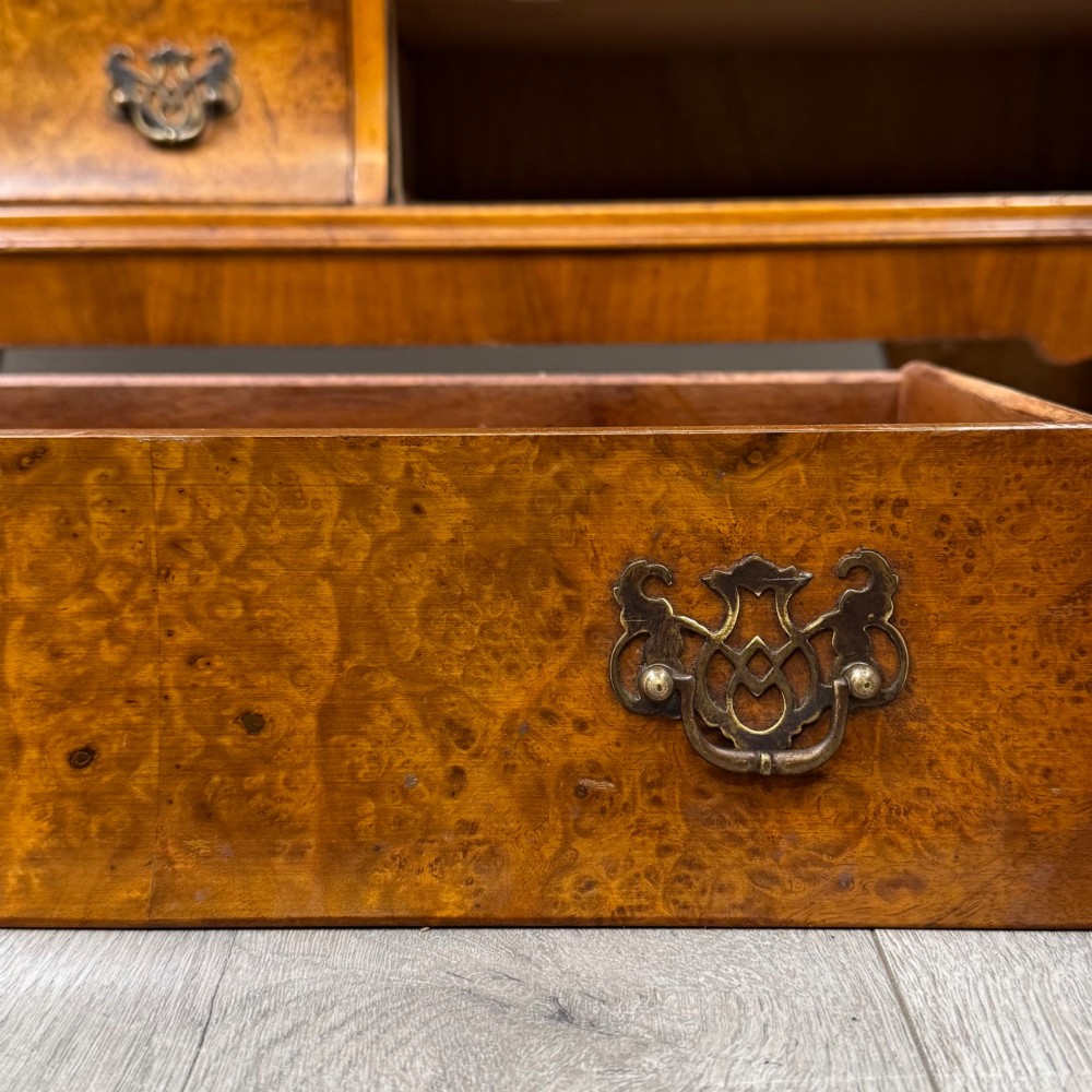 A 20th-century burr walnut display cabinet featuring two glazed doors with arched detail above two drawers on bracket feet. View XII