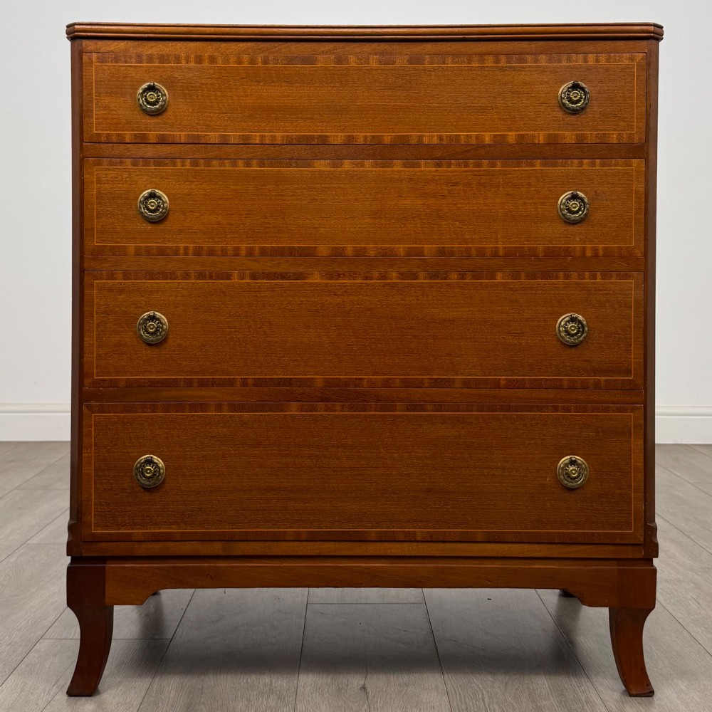 A mahogany chest of four drawers featuring decorative inlaid borders, circular brass drop handles, and bracket feet.