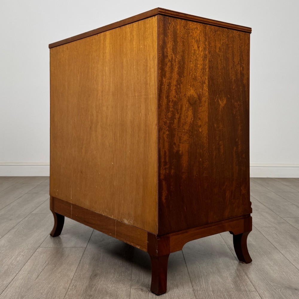 A mahogany chest of four drawers featuring decorative inlaid borders, circular brass drop handles, and bracket feet. View VI