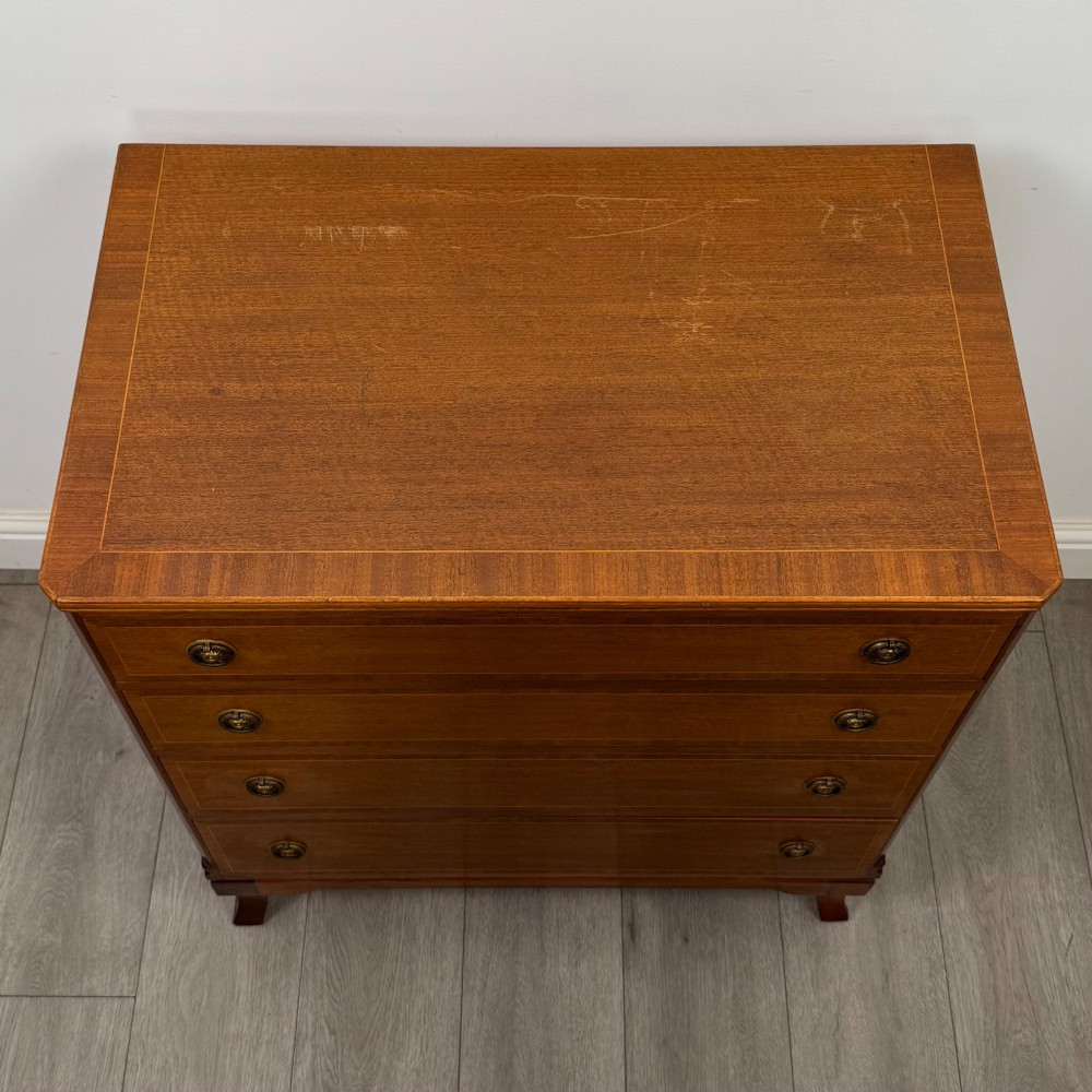A mahogany chest of four drawers featuring decorative inlaid borders, circular brass drop handles, and bracket feet. View IX