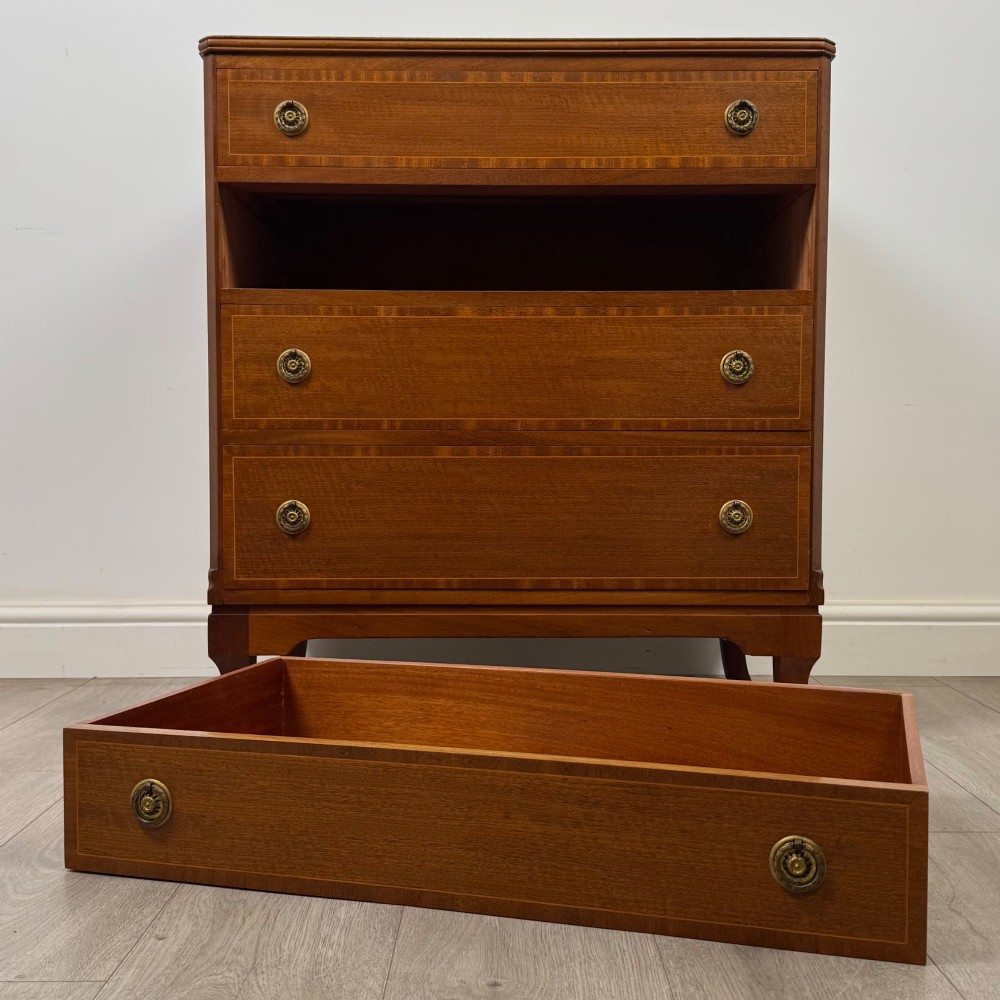 A mahogany chest of four drawers featuring decorative inlaid borders, circular brass drop handles, and bracket feet. View X