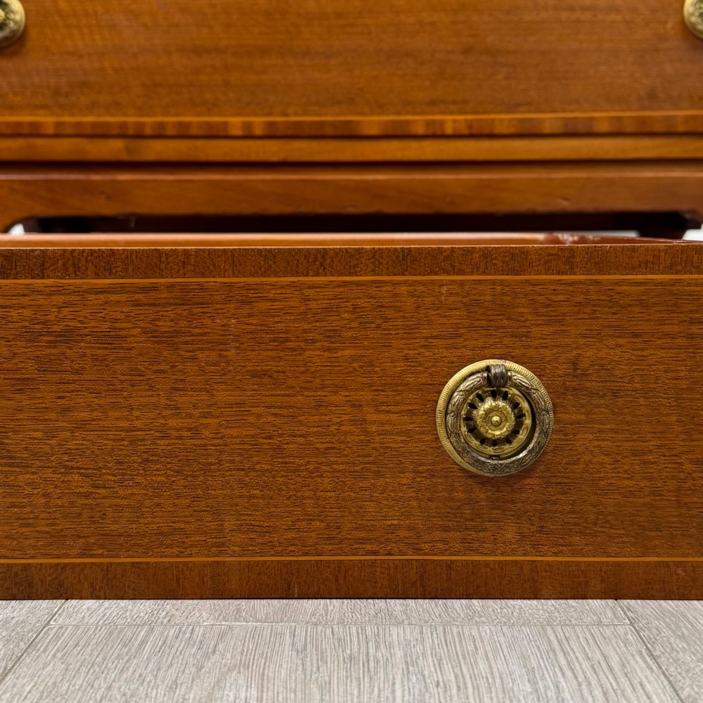 A mahogany chest of four drawers featuring decorative inlaid borders, circular brass drop handles, and bracket feet. View XI