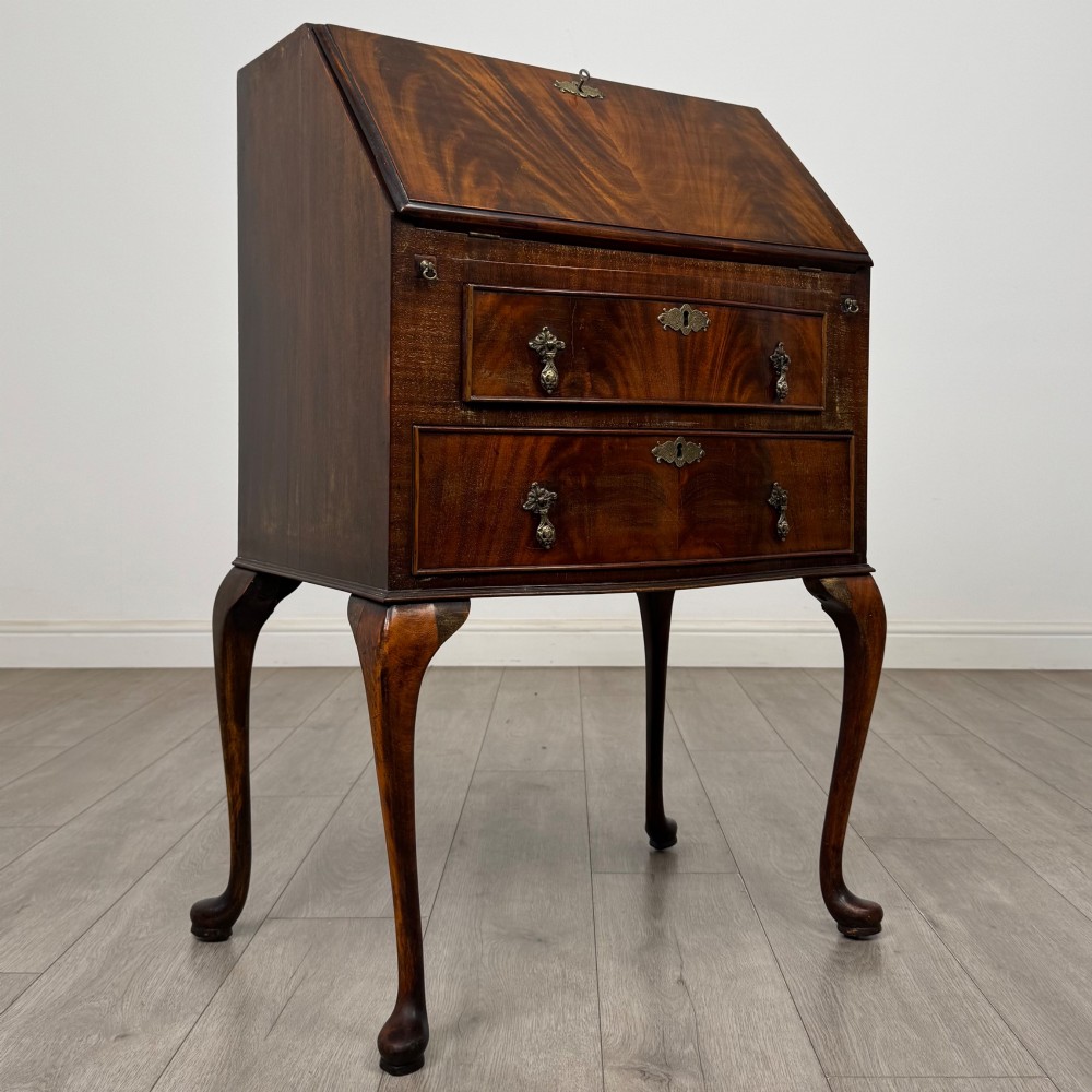 An Edwardian mahogany writing bureau featuring a sloped drop-front lid above two drawers, supported by four slender cabriole legs. View IX