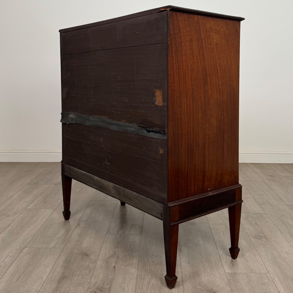An 18th-century Georgian mahogany cupboard featuring flame veneer panelled doors, upper drawer section, a fluted apron, and tapered legs. View VII