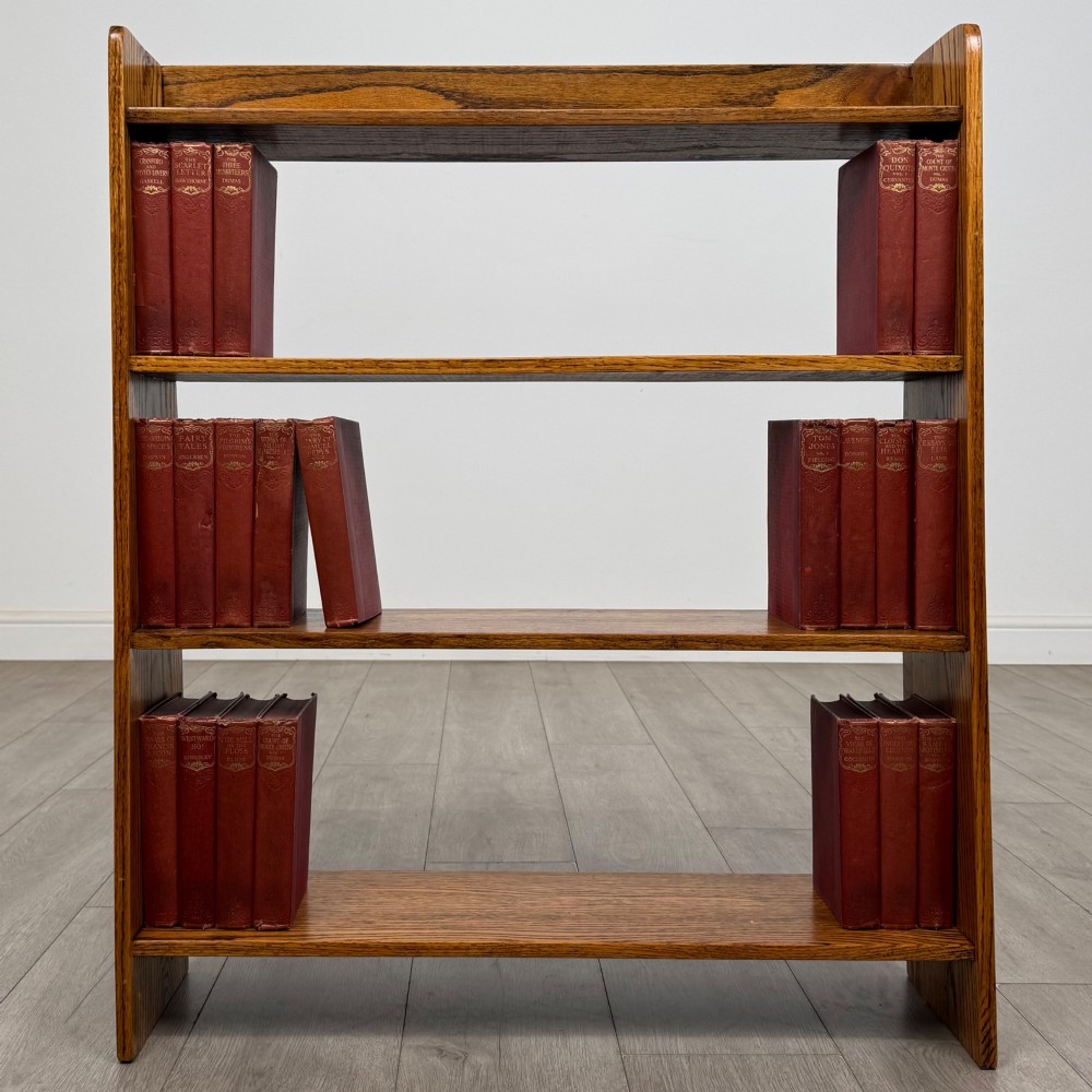 An open golden oak bookcase featuring four horizontal shelves arranged vertically with solid side panels.