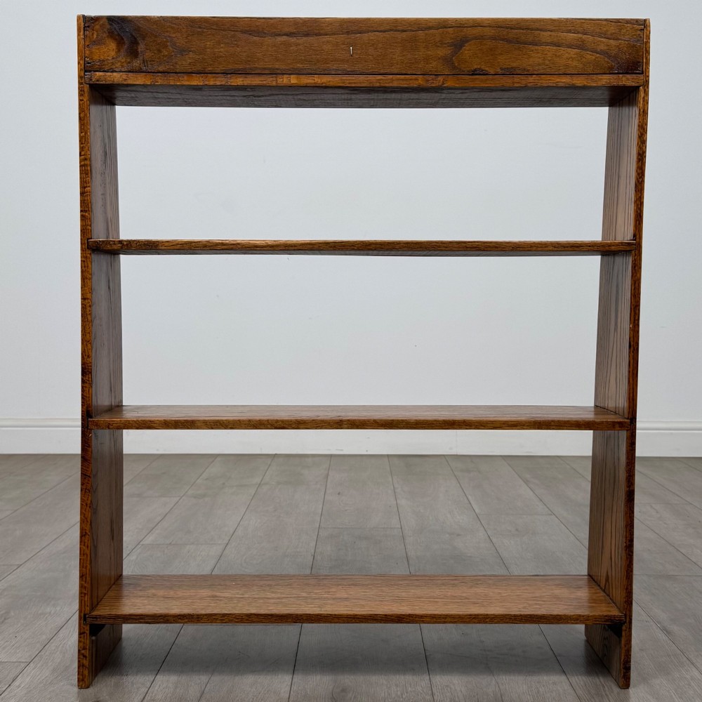An open golden oak bookcase featuring four horizontal shelves arranged vertically with solid side panels. View VI