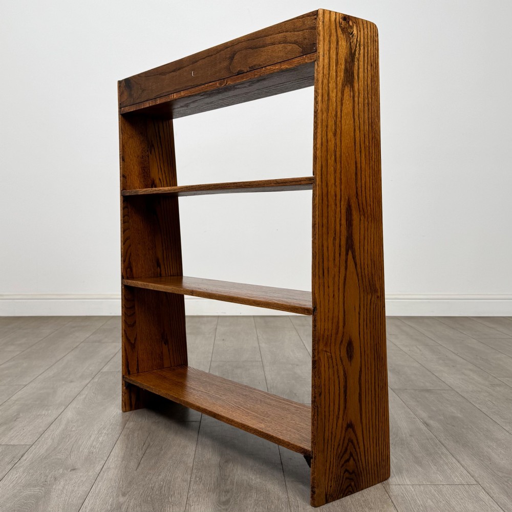 An open golden oak bookcase featuring four horizontal shelves arranged vertically with solid side panels. View VII